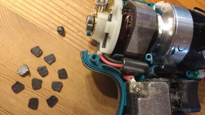 Isärtagen elektrisk maskin med lösa, svarta bitar på träbordet.