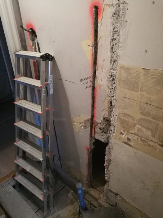 Badrumsrenovering med osäker vägg för montering av tvättställ, synligt rörarbete och stegar framför väggen.