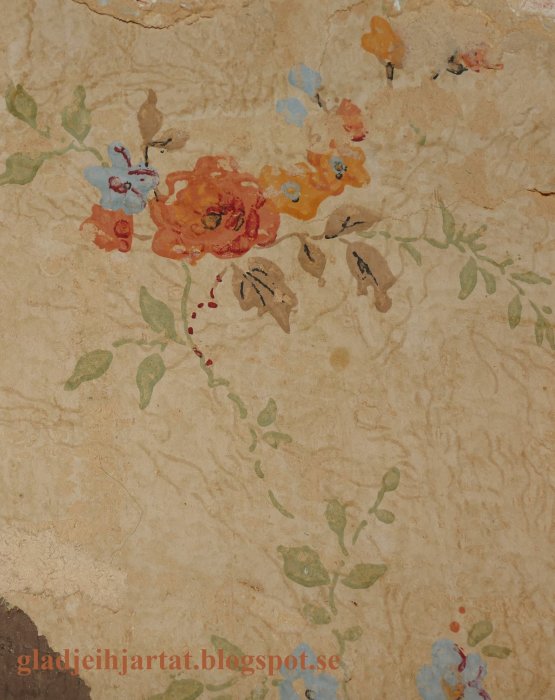 Närbild av en gammal tapet med blommönster och flerskiktsväggstruktur som syns.