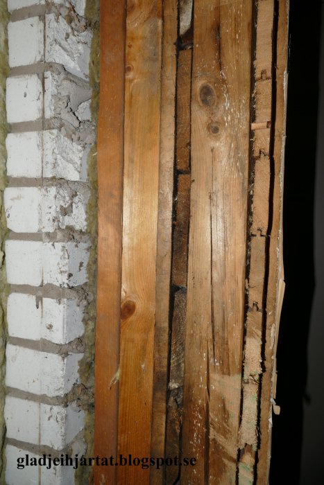 Vertikal sektion av en vägg som visar flera lager tapet, träreglar och isolering.