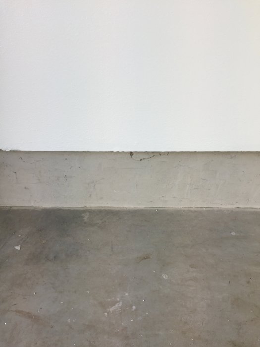 Ett betonggolv och en vit vägg med synligt mellanrum vid anslutningen som är cirka 2.5cm djupt.
