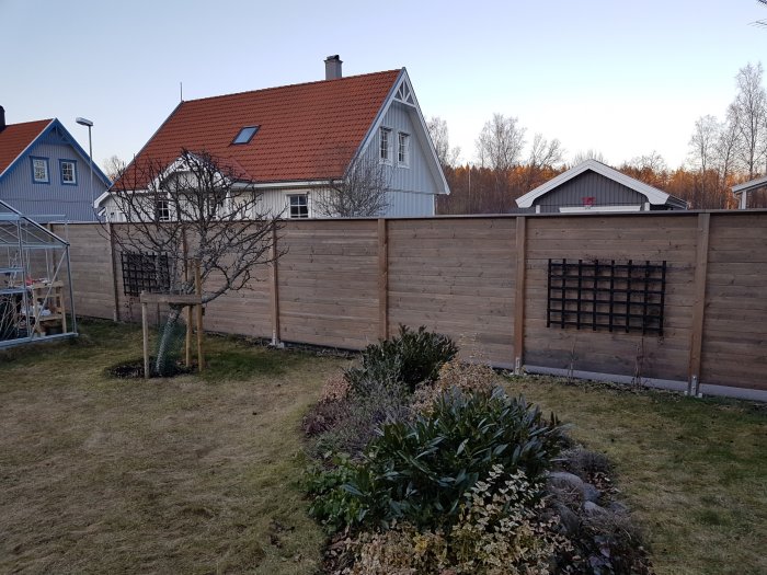 Trädgård med en nybyggd 1,8 meter hög staketsektion mellan stolpar, inkluderar en överliggare och dekorativt galler.