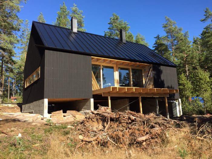 Nytt hus med mörkt, buckelfritt tak av Planja Trend och svart stående träpanel på fasaden.