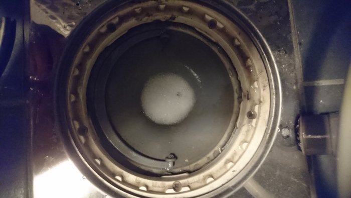 Öppen avloppstumlare med synligt fix/spackel och smuts runtomkring.