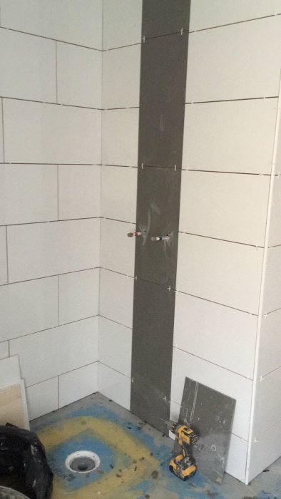 Vägg före klinkersättning med tätskikt synligt och kakelkryss mellan plattorna.