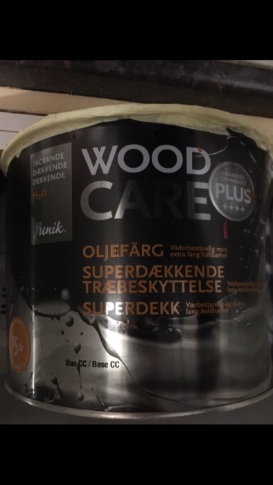 Burk med oljebaserad träskyddsfärg märkt 'Wood Care', för användning på hus och staket.