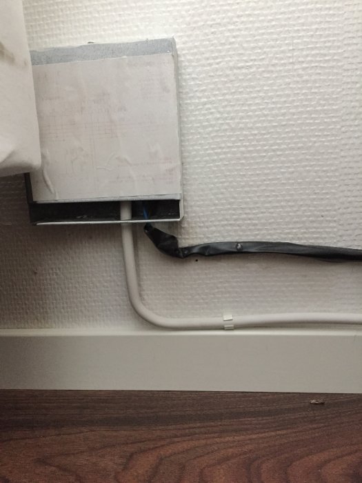 Radiator flyttad 50 cm, med flexibel koppling inlindad i svart eltejp och fastsatt vid vägg.