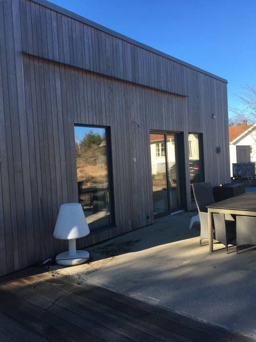 Isolerad gjuten platta med avrinningsplåt ovanpå, i anslutning till lärkträfasad på hus.
