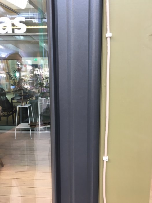 Närbild på en antracitgrå skjutdörrsprofil intill en olivgrön vägg, vilket illustrerar färgalternativ för uterumsbygge.