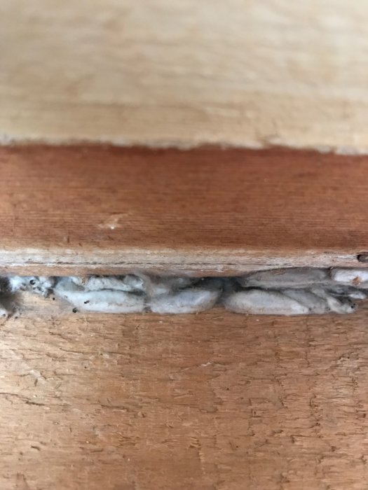 Skarv mellan gammalt innertak och vägg med okänd gråvit ansamling i trähus under renovering.