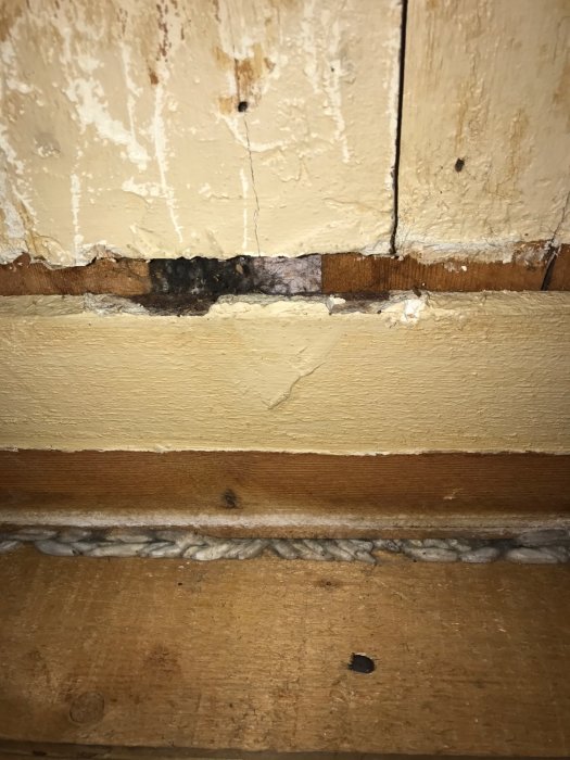 Svart ansamling vid skarven mellan gammalt innertak och vägg i renoveringsprojekt.