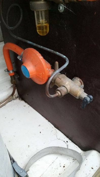 Läckande gasregulator och anslutning monterad i en husvagn, behöver underhåll eller utbyte.