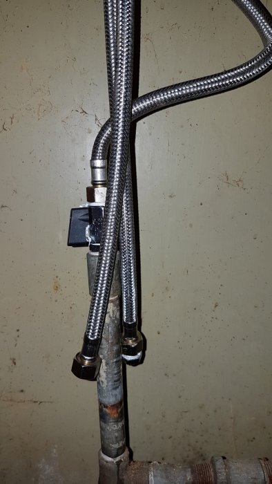 Rörinstallation under vask med öppen ventil och anslutna slangar, en pluggad, en till diskmaskin.
