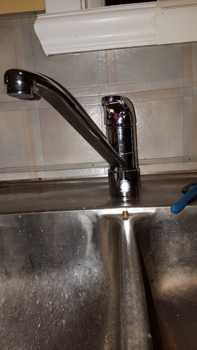 Kökets vattenkran ovanför diskbänk med droppar och ventil i öppet läge.