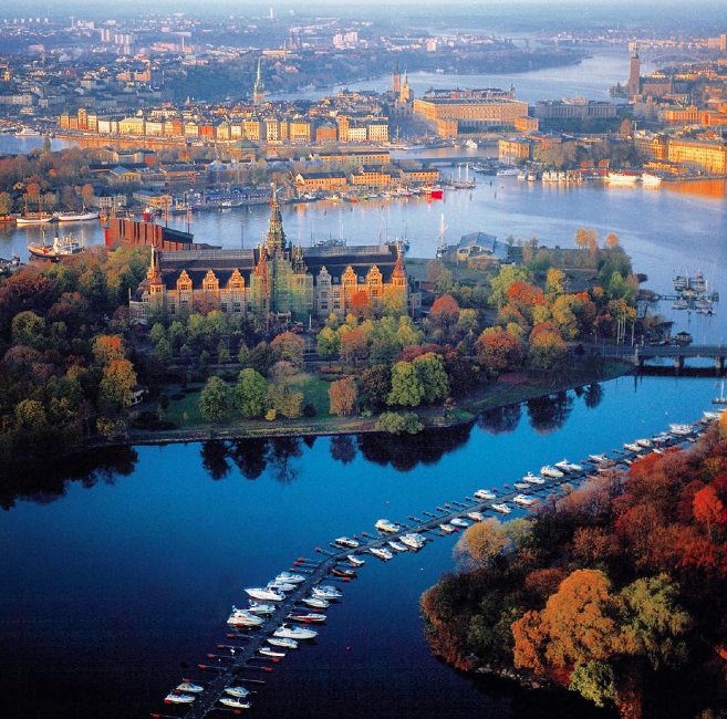 Flygbild över stad med floder, broar och färgglada byggnader under hösten.