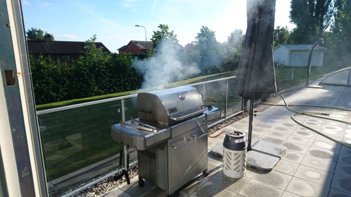 Rökig gasolgrill på trädäck, används till matlagning med en gasflaska intill.