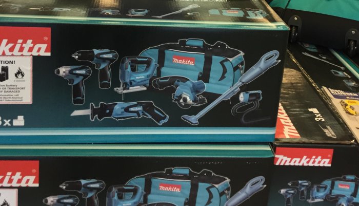 Makita verktygskit i blå färg med borrmaskiner, såg och ficklampa i butiksdisplay.