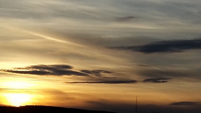 Solnedgång med dramatiska moln i Falun, gyllene himmel vid horisonten.