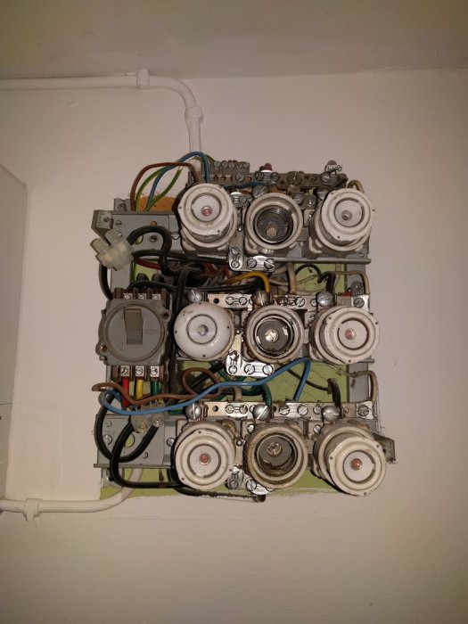 Gammal elcentral med flera säkringar, ledningar och anslutningar i behov av modernisering.