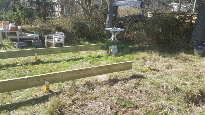 Träreglar och markskruvar i ett pågående arbete för att bygga ett trädäck utomhus.