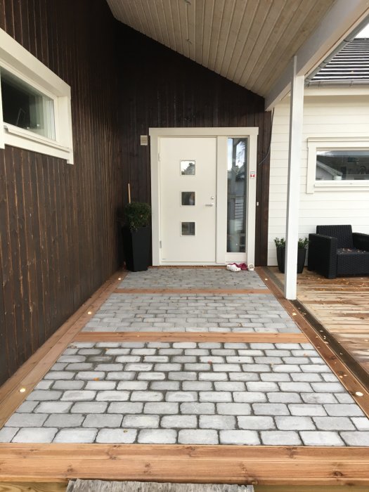 Brun trall på nybyggd altan med stenplattor framför, husfasad och altandörr i bakgrunden.