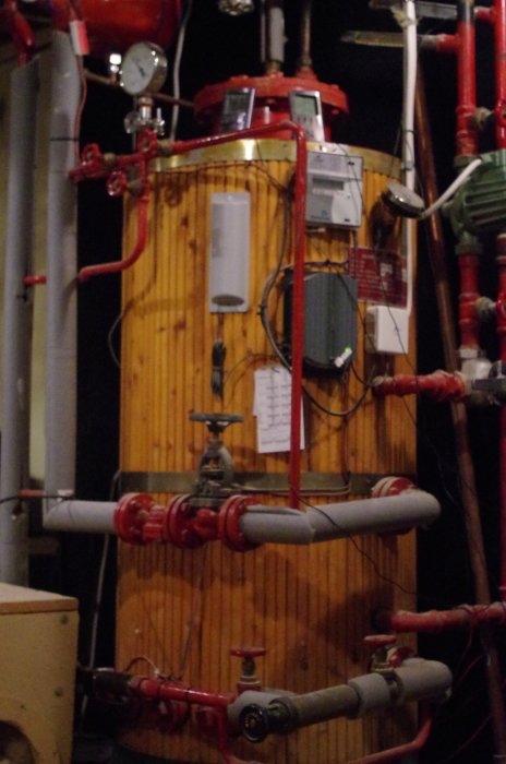 Gammal CTC värmeväxlare och vattenrör i ett upplyst pannrum.