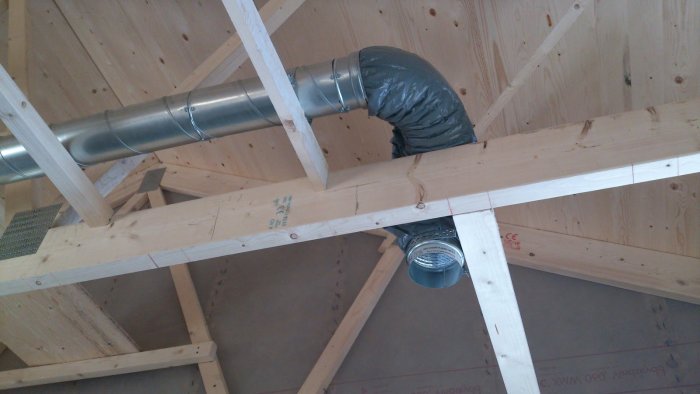 Ventilationsrör monterat längs träbjälkar med isolering och frånluftsventil i taket.