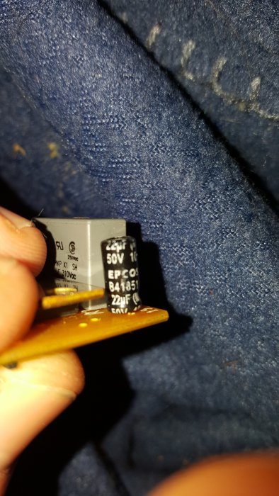 Kretskort med kondensatorer från ett kylskåps startrelä, visande specifikationerna 22µF och 50V.