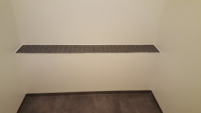 Renoverat badrum med hylla klädd med klinker som sticker ut något från väggen.