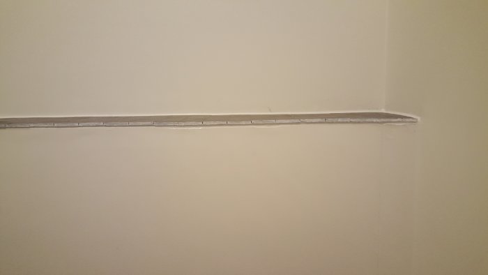 En ojämnt skuren kant på en hylla med synlig silikon och klinkers som sticker ut.