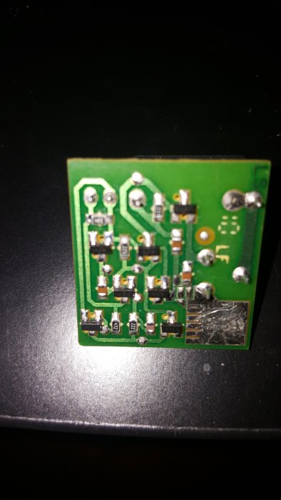 Elektronisk kretskort med olika komponenter som resistorer och kondensatorer på en svart bakgrund.