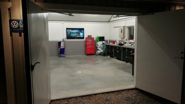 Välorganiserat garage med verktygsskåp och TV på väggen, inga skarvsladdar synliga.