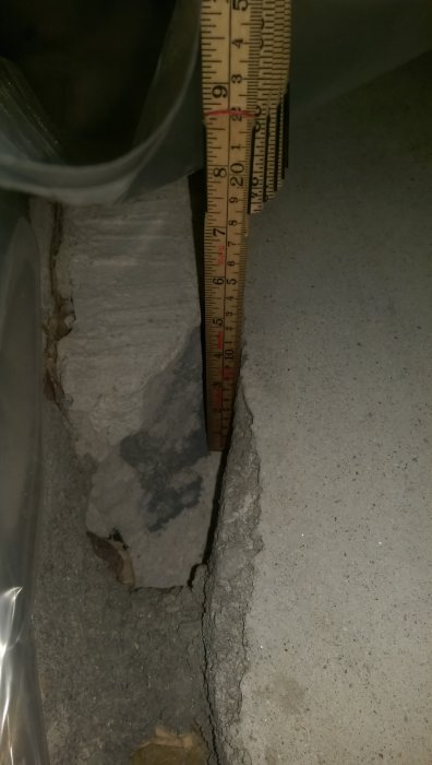 Mätning av sprickdjup i betonggolv med tumstock, visar cirka 20 centimeter.