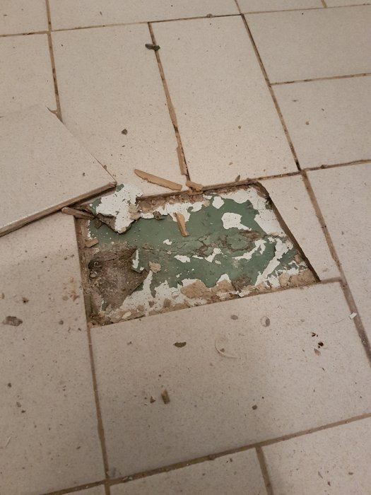 Skadade keramiska plattor med en synlig hålighet och trasiga bitar runt öppningen.