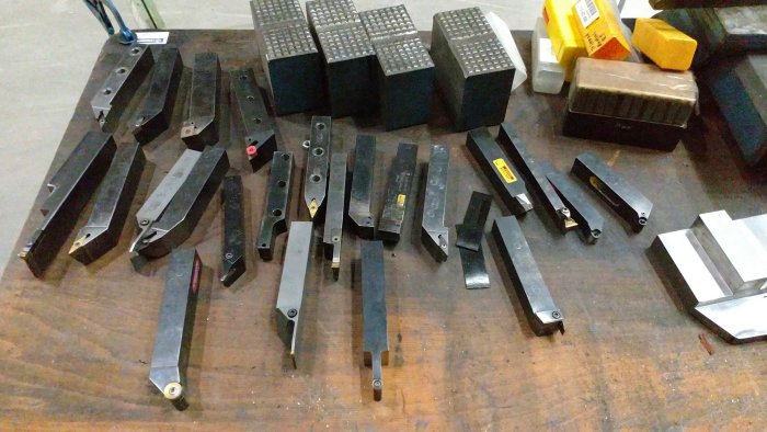 Arbetsbänk med upplagda svarvverktyg och metallblock, potentiella verktyg för metallsvarvning.