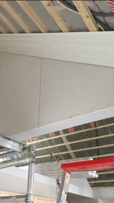 Nydraget el, monterad vit takpanel och osminkade gipsskivor i ett byggprojekt.
