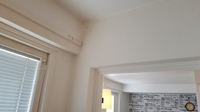 Inomhusvy av en vit vägg och tak med dörröppning, indikerar en möjlig bärande struktur.