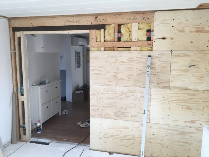 Renoverad väggöppning med ny 15mm plywood, nu ca 45cm bredare, i en halvfärdig inomhusmiljö.