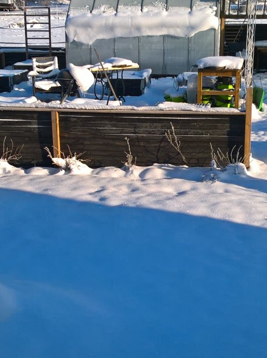 Grill täckt med snö i en trädgård vid -12 grader, indikerande vintergrillning.