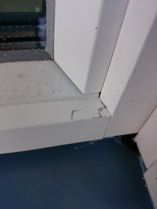 Närbild av repor på en vitmålad aluminiumfönsterkarm.