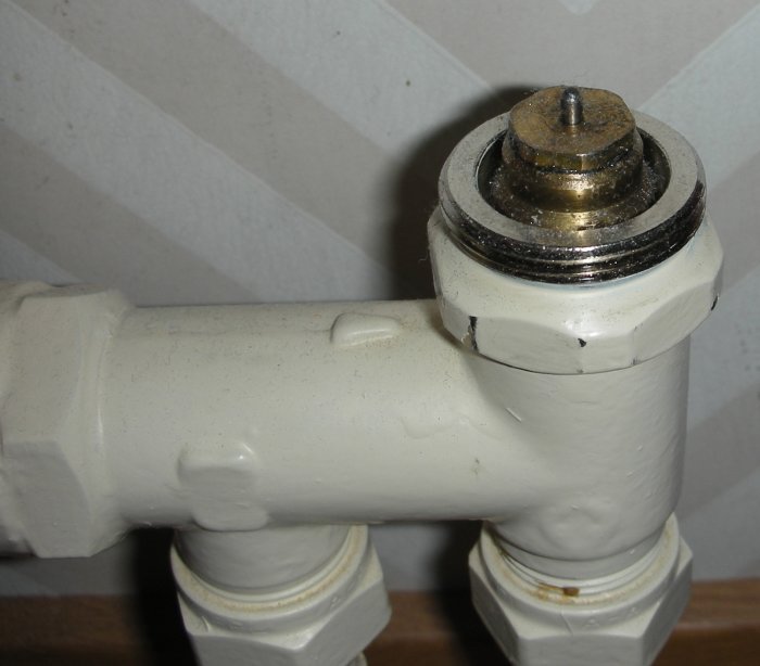 Närbild på en vitmålad gammal radiatorventil med synlig gänga som kan vara M26 storlek.