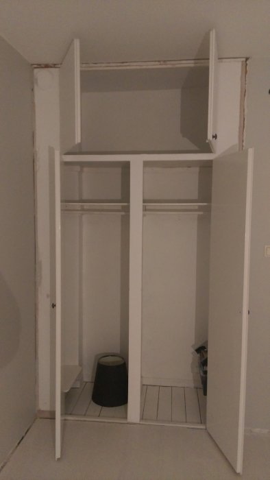 Tom garderob utan dörrar där ena väggen är plywood, med synlig list upptill.