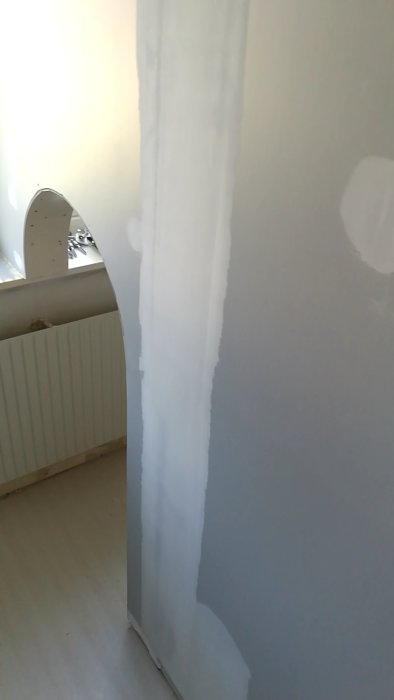 Vägg i rum under renovering med bredspackling längs en skarv.