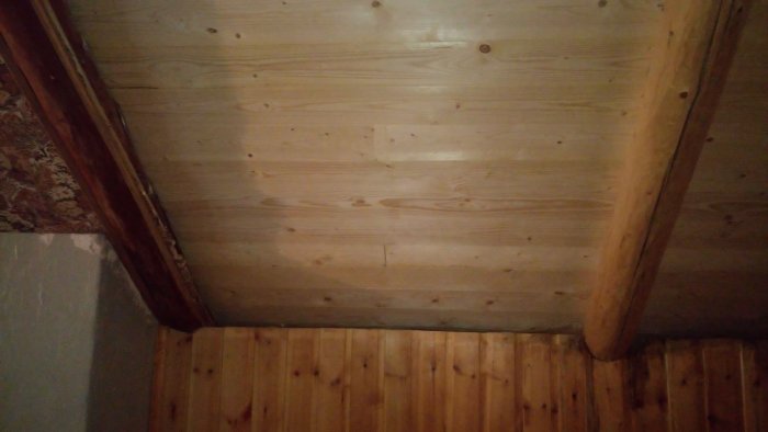 Interiörbild av en del av ett trähus, visande timmerväggar och tak där isoleringen övervägs för renovering.