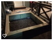 Trädäck integrerat med en öppen sandlåda i kvällsbelysning, avsedd för luckmontering och kattskydd.