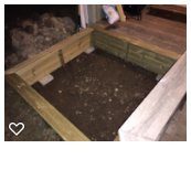 Sandlåda integrerad med trädeck, öppningsbar bräda längs ena kanten för lastnätskattskydd.