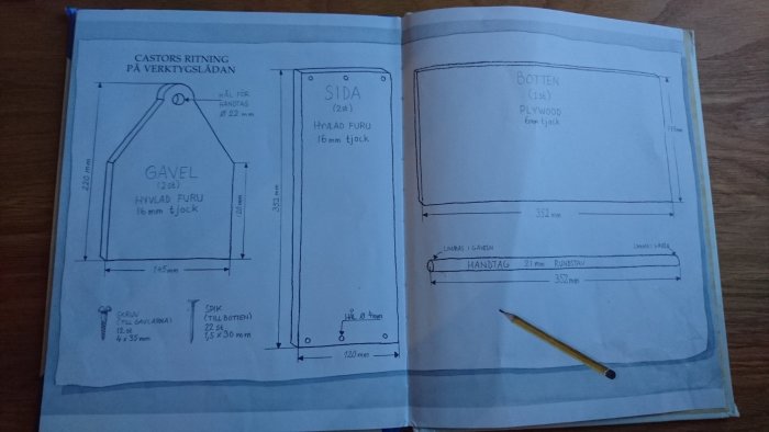 Ritningar för en verktygslåda på öppen bok med mått, materialbeskrivning och penna liggandes på sidan.