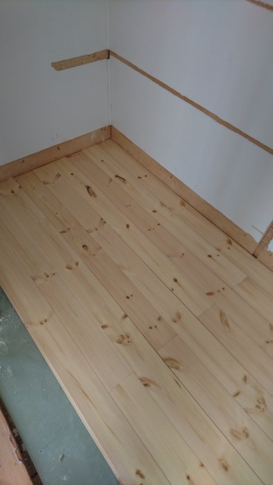 Nytt trägolv lackat, väggar med pärlspont i ombyggd garderob under renovering.