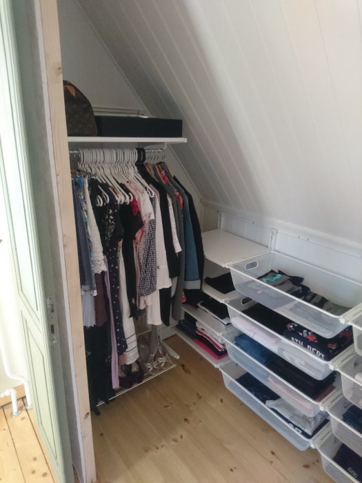 Renoverad walk-in-garderob med pärlspontsväggar, klädhängare och IKEA-hyllsystem på ett lackat trägolv.
