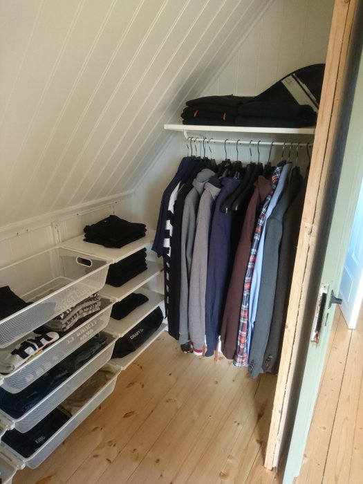 Nylackat trägolv och vit pärlspontsvägg i en välorganiserad garderob med IKEA-inredning.